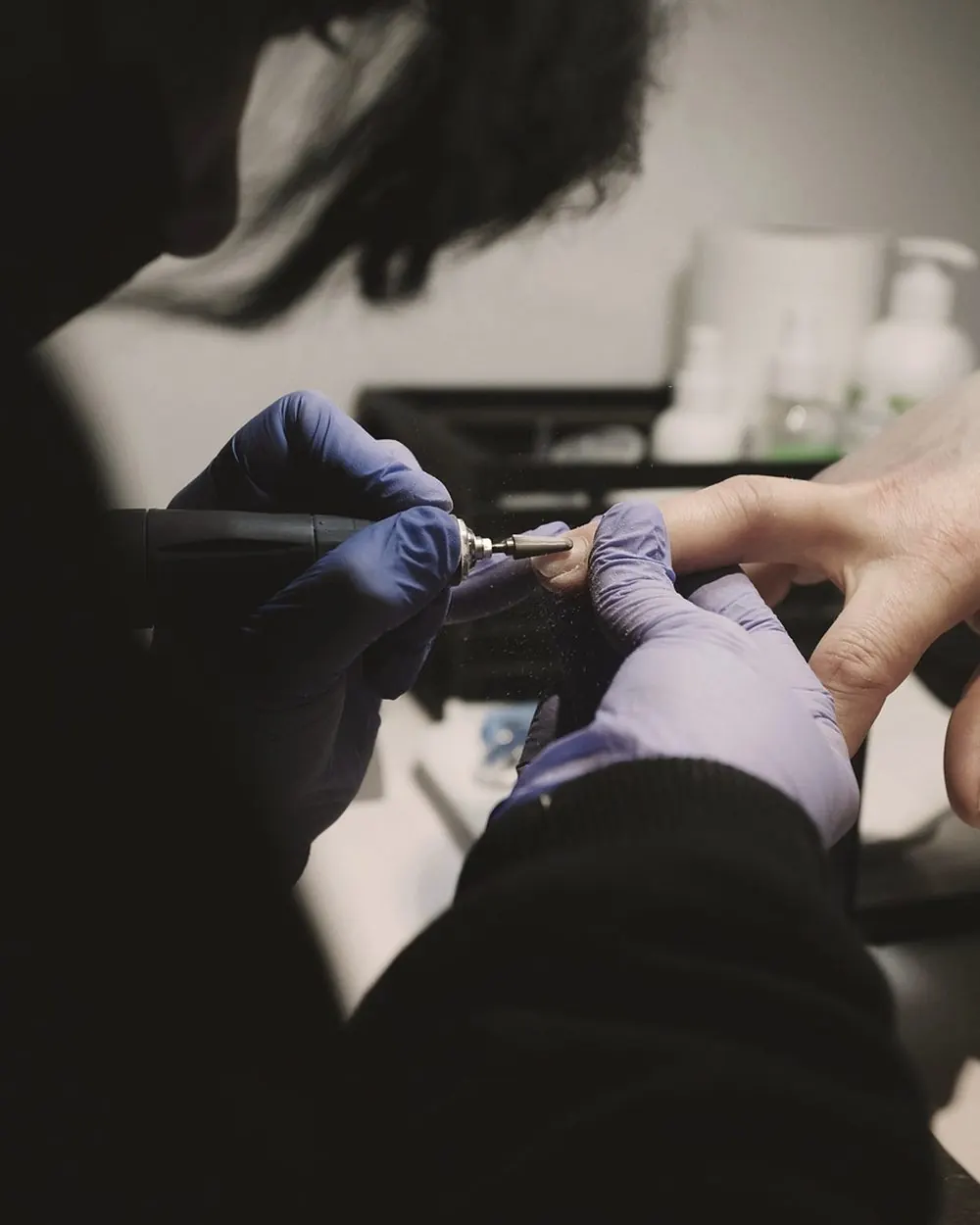 Préparation de l'ongle à la ponceuse, mains gantées