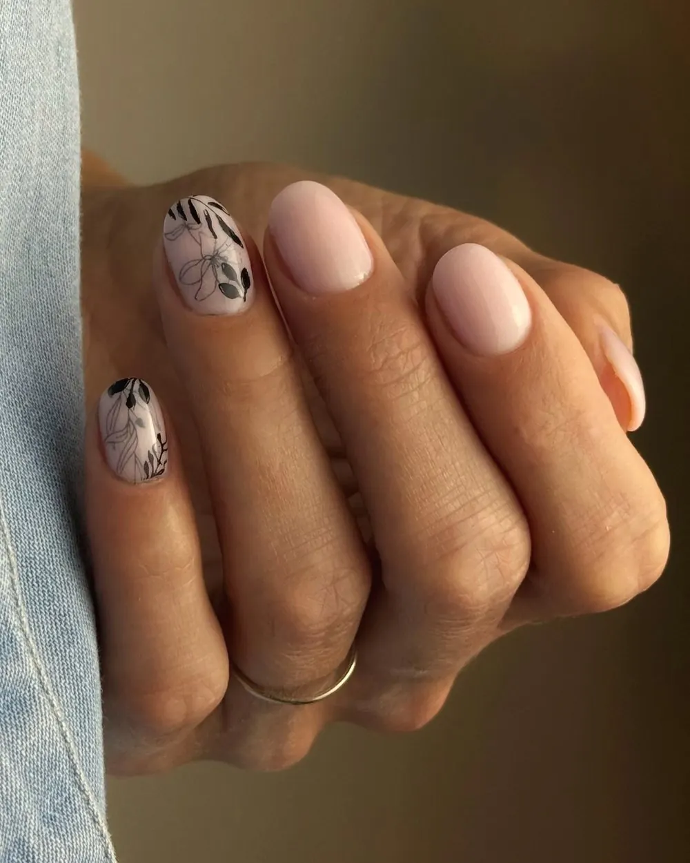 Ongles nude rosé et feuillage noir, sur une chemise en jean